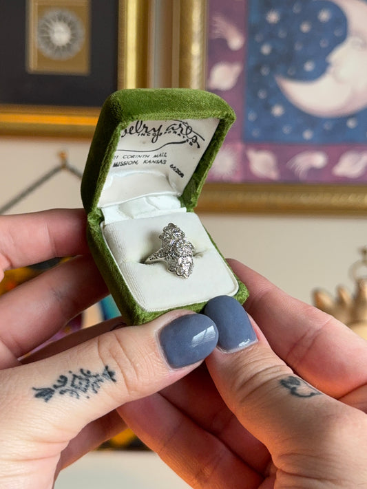 Antique shield ring with ornate filigree and diamond cluster.