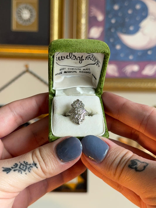 Antique shield ring with ornate filigree and diamond cluster.